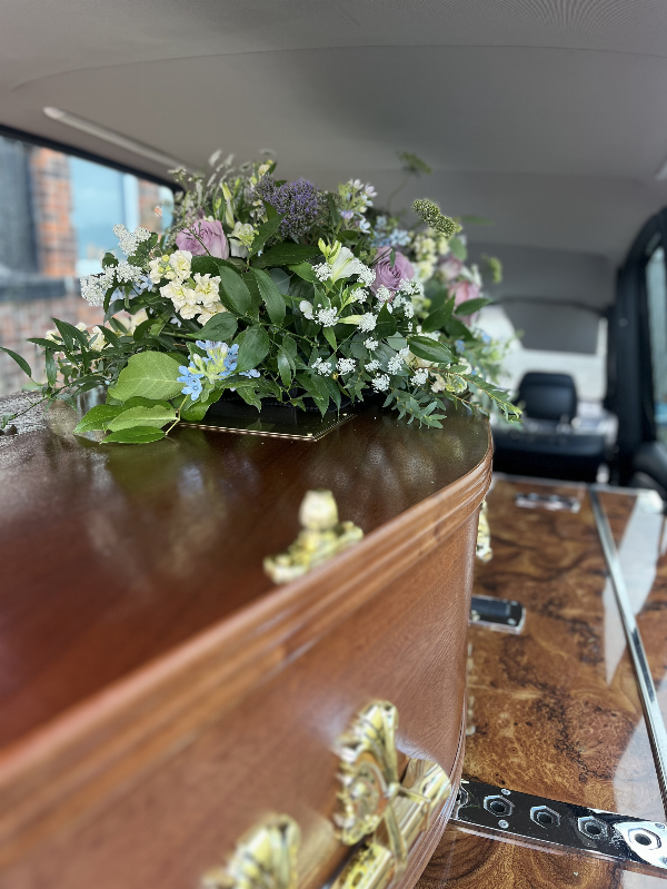 Coffin in the hearse adorned with funeral flowers