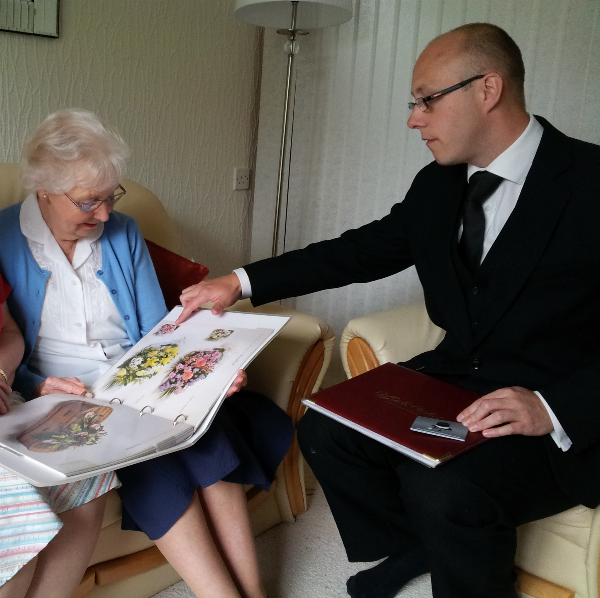 A funeral director helps an elderly lady make funeral arrangements including a funeral plan